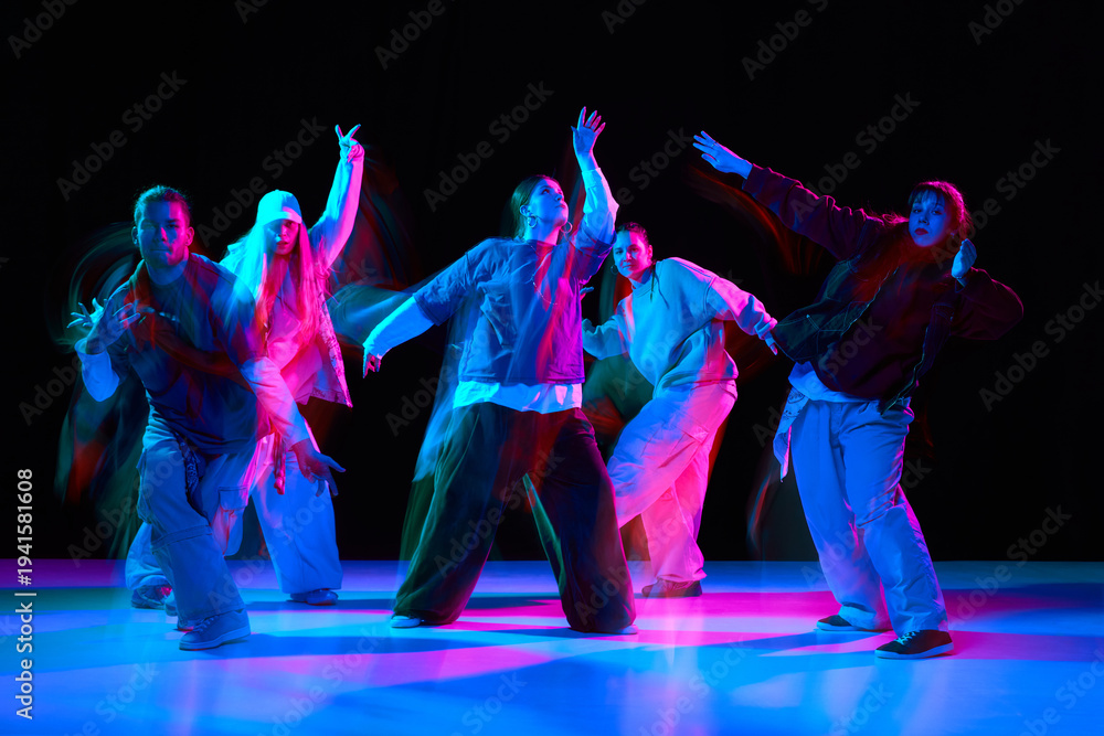Obraz premium Hip hop dancers performing synchronized street dance with neon lighting and motion blur. Urban music culture scene for advertising, entertainment branding, nightlife promotion and youth marketing