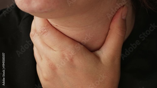 Woman with sore throat touching neck with a hand, suffer from painful swallowing, tonsillitis, irritation or thyroid gland salivary disease