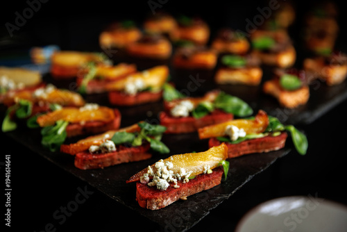 Assorted crostini appetizers with blue cheese and pear on dark stone board