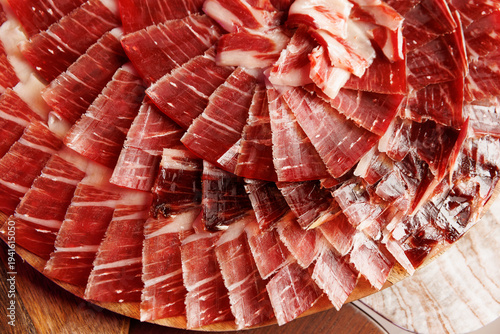 Sliced Spanish Jamon Iberico ham arranged on a wooden board