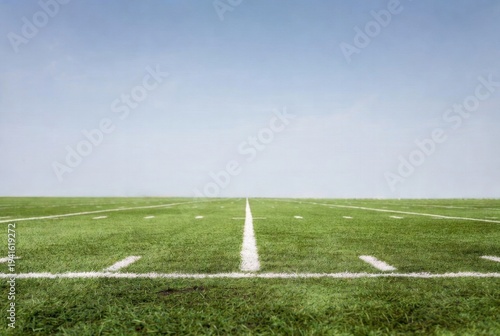 Wide-angle view of green football field near 1-yard line with white hash marks under clear blue sky