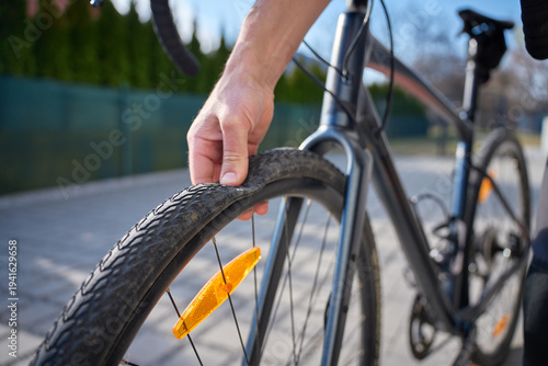 Photography Hand squeezes bicycle tire to check pressure after puncture on bike on paved street