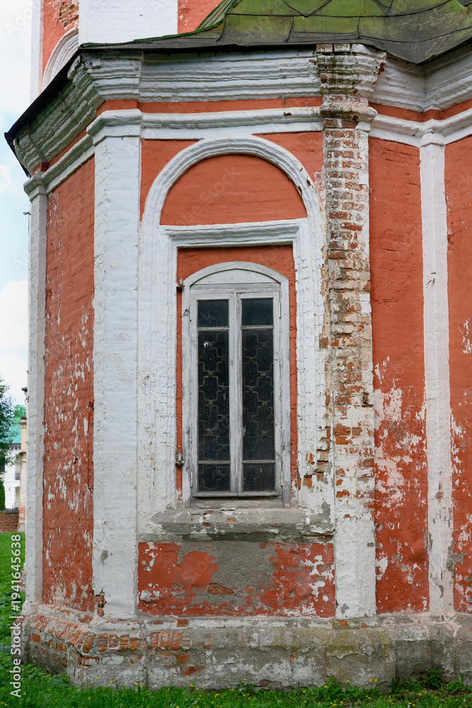 Obraz premium A window in the arched opening of the brick wall of a medieval church in Pereslavl-Zalessky, in the process of restoration