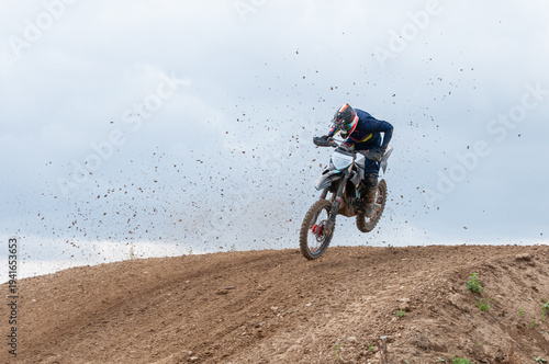 Unrecognized athlete riding a sports motorbike jumping on the air on a motocross race. Fast speed extreme sport.