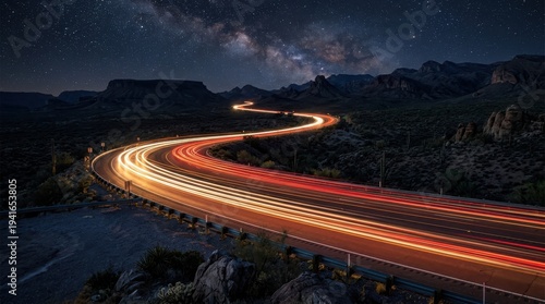 Vivid light streaks paint a winding mountain road at night under a starry sky, capturing the essence of travel and motion.