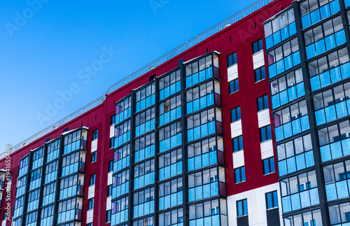 An apartment building with lots of balconies against a blue sky background