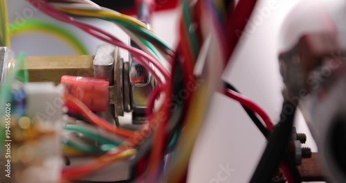Close-up of a technician loosening a screw on electrical equipment surrounded by colorful wires. Technical maintenance and repair of electronic components, showing industrial work, wiring systems, and