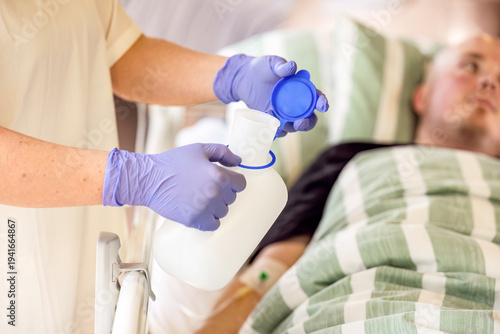 Nurse holding urine bottle for male patient in hospital bed, basic nursing care and hygiene assistance