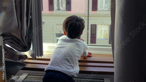 Canvas Print Young boy leaning on windowsill, gazing outside, deep in thought, quiet moment o