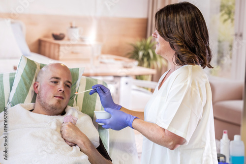 Foto Young male patient with spastic contracture receiving assisted feeding from nurs