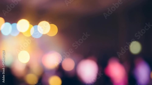 Slow motion pan shot of blurred crowd moving past colorful stage lights at night in indoor concert venue