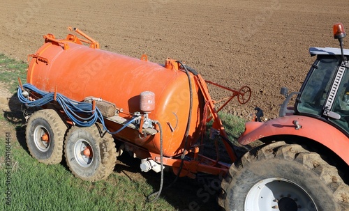 Wallpaper Mural Side view of an orange liquid manure spreader trailed by a tractor at the edge of a plowed field. Copy space. Torontodigital.ca