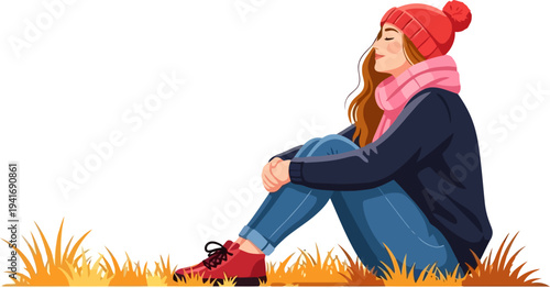 Relaxing woman sitting on golden autumn grass in a winter hat