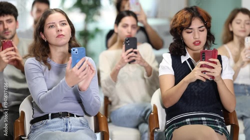 Young learners sitting and scanning QR codes with smartphones in modern educational setting