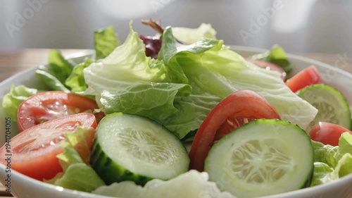 Fresh vegetable salad with lettuce, cucumber and tomato slices in bowl on table, healthy food concept for diet nutrition, clean eating, home cooking and restaurant menu.
