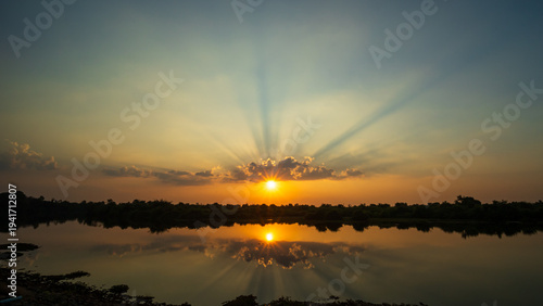 Golden Sunset Reflecting Over a Tranquil Lake with Radiant Sun Rays and a Serene Natural Landscape