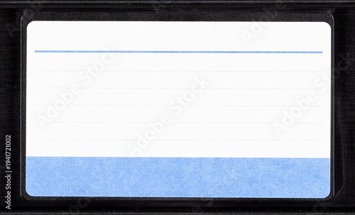 Blank VHS cassette label with blue lined sticker on black videotape cartridge, front view closeup isolated on white background, 80s 90s retro analog home video archive mockup template with copy space