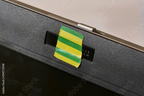 Obraz na plátne Laptop webcam covered with yellow green striped tape, macro detail closeup of bl