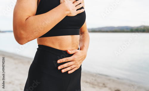 Female performing breathing exercise with hands on chest and abdomen in nature by riverside