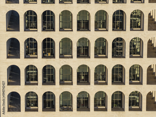 Aerial view of the Palazzo della CiviltÃ  Italiana, its repetitive arches reflecting the sunlight, a symphony of light and shadow, Rome, Lazio, Italy.