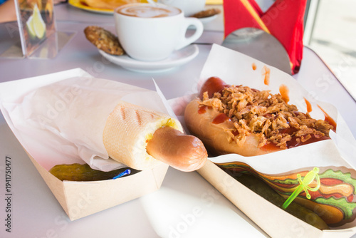 Tasty hot dog with grilled sausage, salt cucumber, mustard and crisps