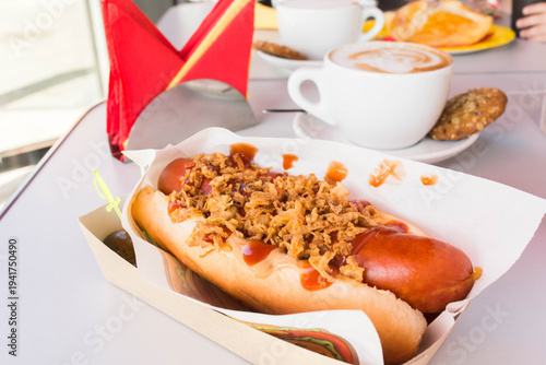 Tasty hot dog with grilled sausage, salt cucumber, mustard and crisps