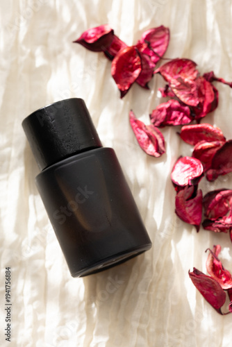 Dried Roses with Black Perfume Bottle on Fabric
