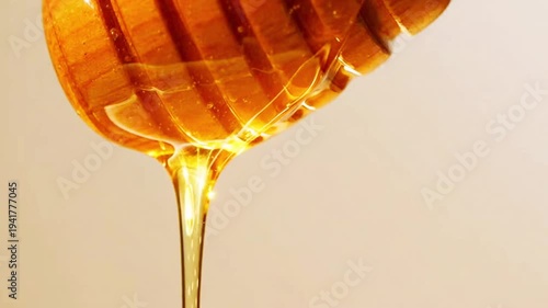 Close Up Shot Of Golden Viscous Liquid Honey Dripping Slowly From A Wooden Dipper Utensil Against A Clean Bright Background Illustrating Sweet Food