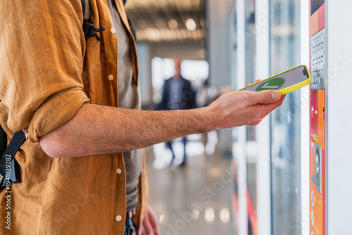 Foto Traveler paying with smartphone at vending machine in airport