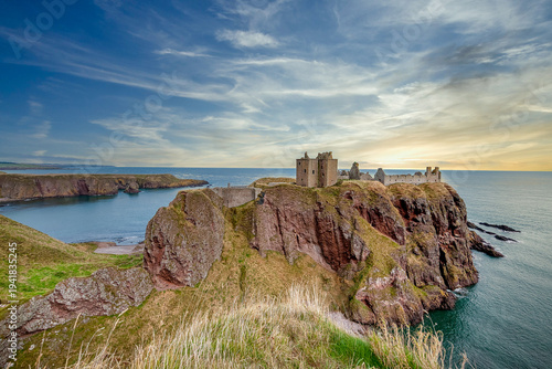 Dunnottar Castle is a medieval castle, now in ruins, perched on a rocky cliff on a headland on the northeast coast of Scotland. United Kingdom