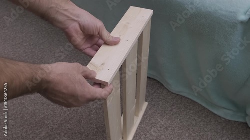 man collects wooden shelf made of planks, slow motion
