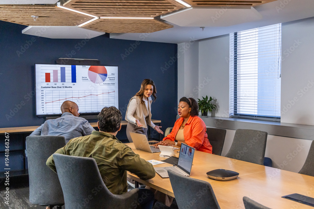 Obraz premium Diverse coworkers presenting charts on wall display in meeting room in office attire using laptops