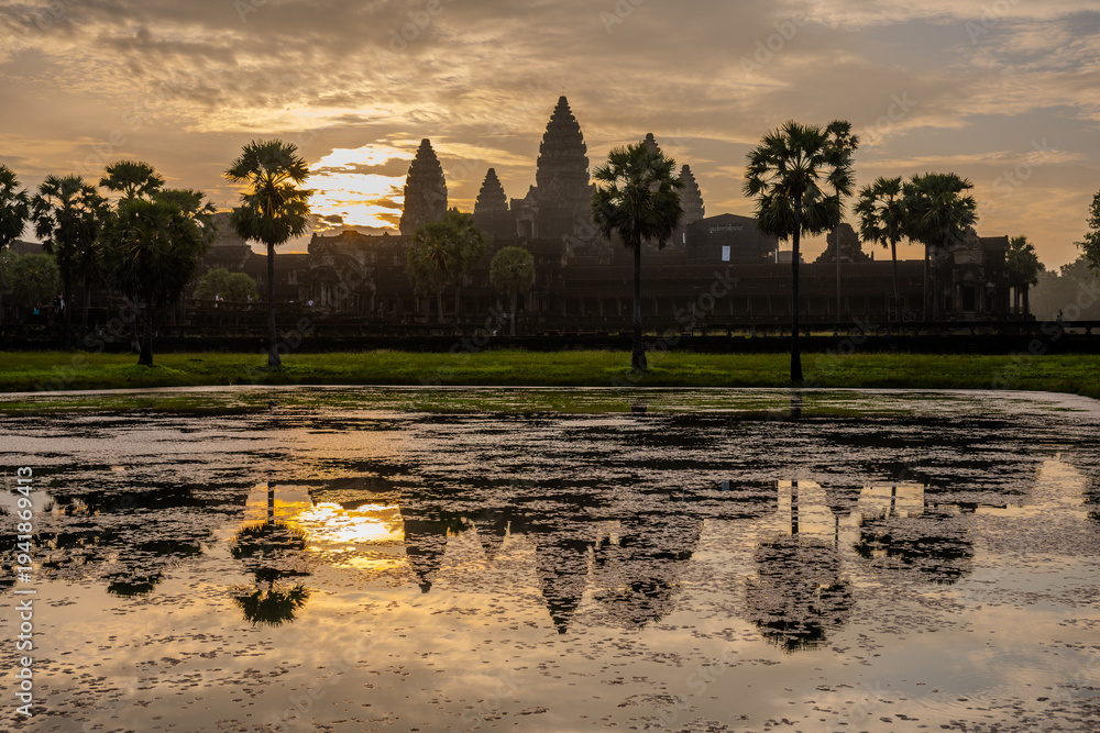 Naklejka premium Angkor Wat temple reflected in a pond at sunrise in Cambodia