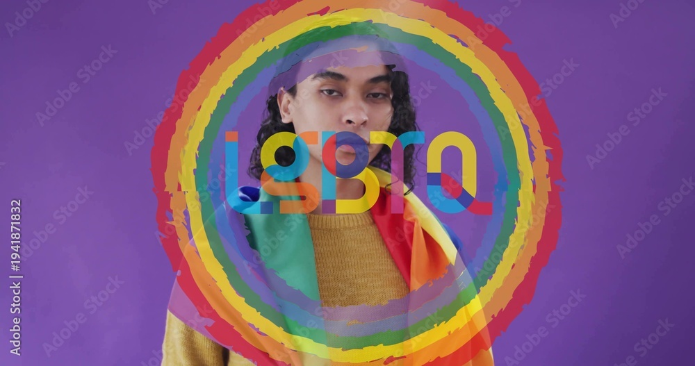 Fototapeta premium Posing person wearing mustard sweater draping pride flag on purple wall with ring overlay letters