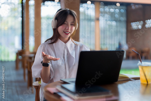 Asian adult woman smiling actively engages video conference call online laptop cafe modern workplace remote communication virtual meeting happy professional learning teaching