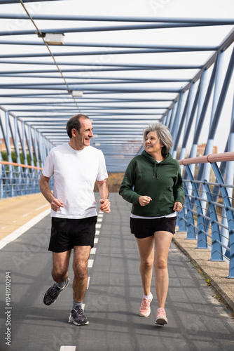 фотографія Happy senior couple exercising together on a modern bridge, staying active and h