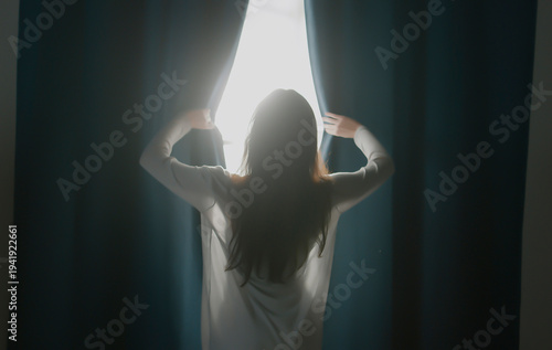 Back rear view confident woman in night robe gown pulling opening lace curtains after waking up in morning, admiring panorama view near big window,enjoying start of new day at home