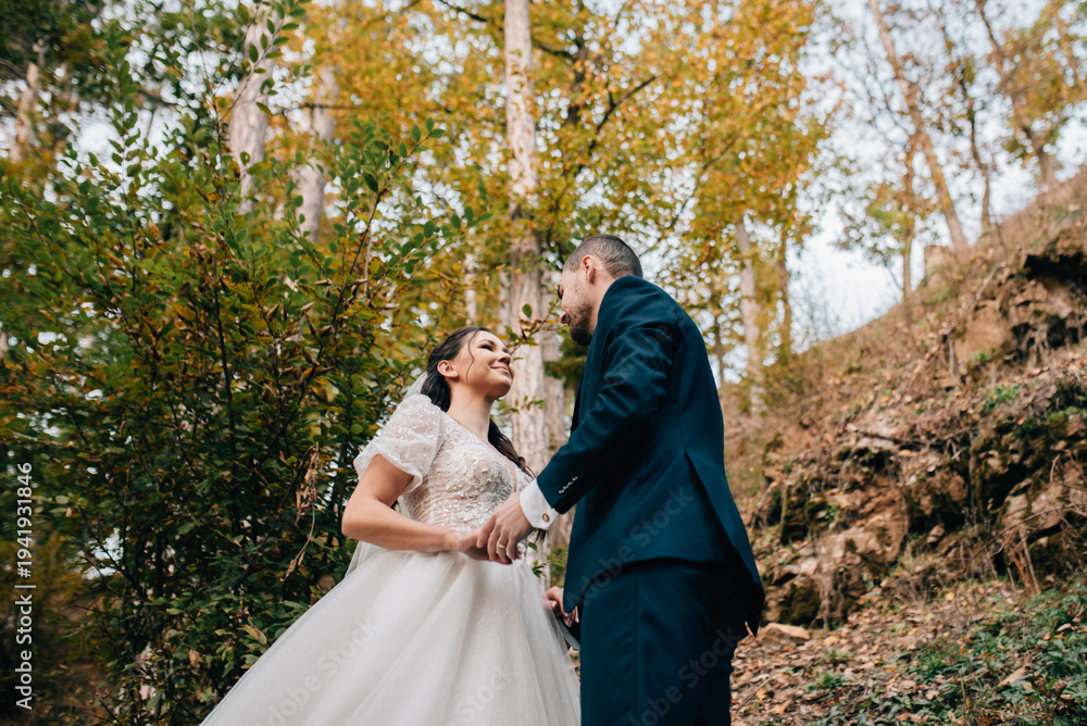 Fototapeta premium Portrait of beautiful bride and an elegant groom in nature, surrounded by a forest.