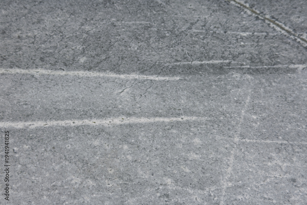 Fototapeta premium Close-up view of textured gray concrete surface with visible scratches and lines