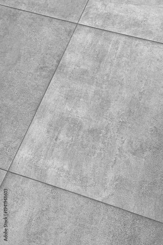 Grey concrete tiled surface with rough industrial texture and diagonal lines forming a unique pattern