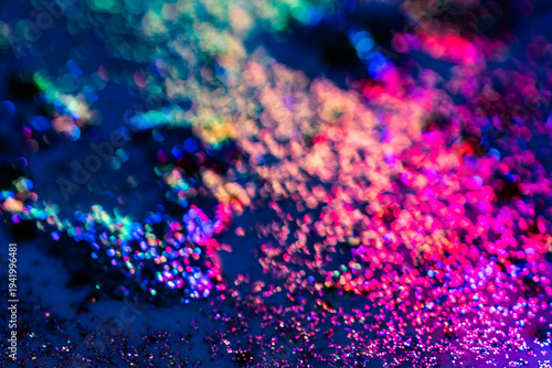 Blurred, defocused background bokeh colorful abstract divorces of oily liquid with neon red, blue and green highlights. Bubbles, stains and shimmering texture create a vivid futuristic background.