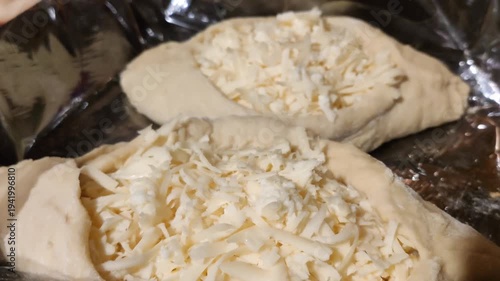 Homemade raw khachapuri bread with rich cheese filling. Traditional culinary heritage and cozy homemade cooking process.