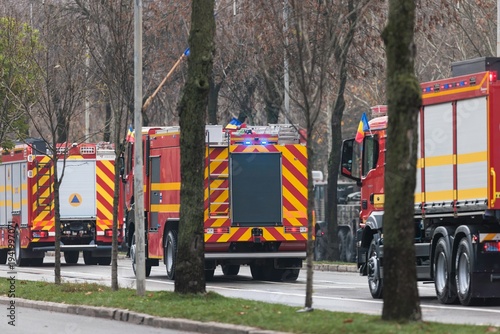 Canvas Print Bright red firefighting trucks move swiftly along the busy urban road, showcasin