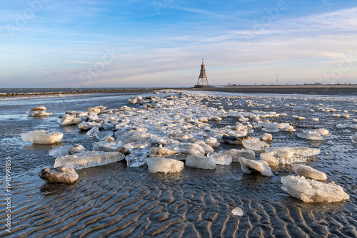Wadden Sea in Cuxhaven, Germany on a frosty winter day with the Kugelbake, a historic aid to navigation at the northernmost point of Lower Saxony, in the background