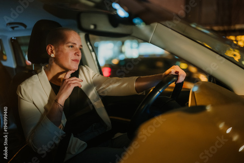 Photography Young woman driving car at night, commuting in urban city, feeling contemplative