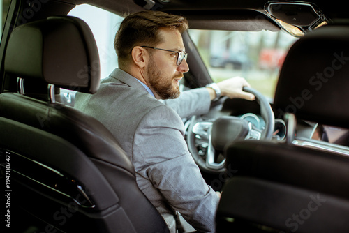 Businessman driving a car on a sunny day in a busy city area