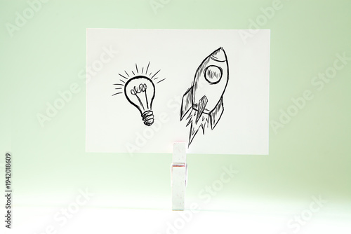 Drawing of rocket and light bulb on white paper. Startup concept