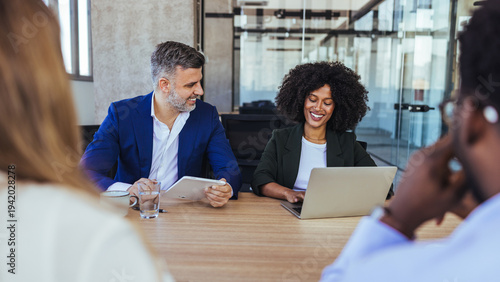 Diverse Colleagues Collaborating in a Modern Office Meeting Around Laptop and Tablet