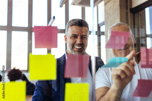 Smiling Colleagues Collaborating Over Colorful Sticky Notes During Creative Business Brainstorming Session