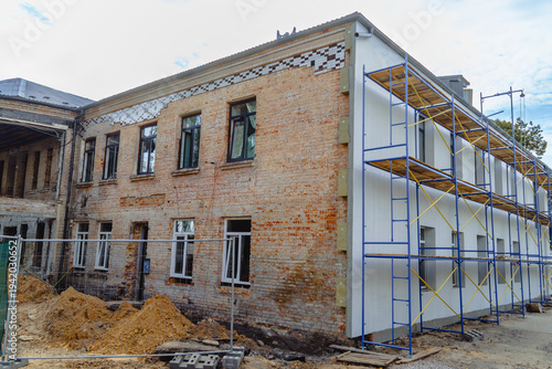 Slika na platnu Renovation and repair of an old brick building with large blue metal scaffolding